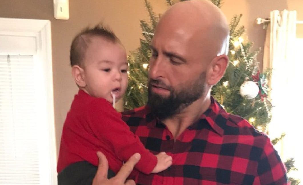 Karl Anderson Takes Family Christmas Photo While His Baby Vomits On Him